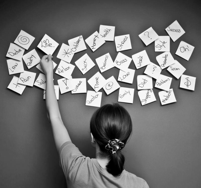 Female person taking a post-it note stuck on a wall amongst many others